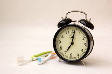 alarm clock standing on white background. toothbrushes are on the table.