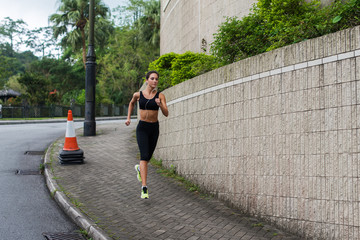 Fit young female jogger jogging on sidewalk in suburban area. Pretty girl working out outdoors.
