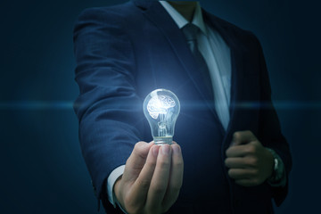 Businessman hand holding a burning light bulb.