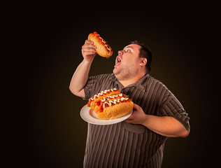Fat man eating fast food hot dog on plate. Breakfast for overweight person. Junk meal leads to...