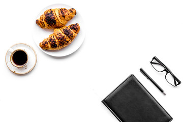 Light breakfast of businessman. Coffee and croissant near notebook and glasses on white background top view copyspace