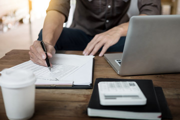 A working wooden desk(table) with notebook computer, coffee cup, paper, pencil and hand