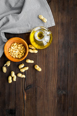Oil for skin care. Peanut oil near peanut in shell on dark wooden background top view copyspace