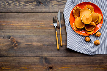 Pile of hot homemade pancakes on bright plate. Dark wooden background top view copyspace