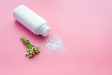 Obraz na płótnie Canvas Soft bath cosmetics for kids with chamomile. Bottle of powder on pink background copyspace