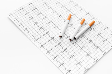Danger of smoking. Cigarettes on cardiogram on white background