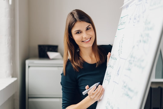 Young cheerful woman standing by flip chart