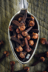 Dry cloves in a spoon on a wooden background