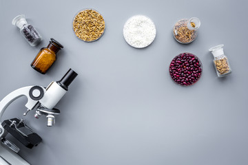 Fototapeta na wymiar Food safety. Wheat, rice and red beans near microscope on grey background top view copyspace