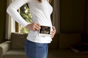 Pregnant woman expecting newborn and holding ultrasound