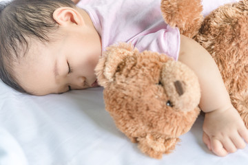 Asian baby sleeping on the bed,thailand people,relax time,bear doll