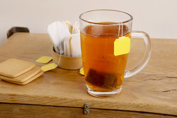 Tea glass cup with tea bag. Black tea cup on wooden table.