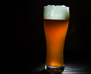 Tall glass of beer on dark wooden background. with copy space.