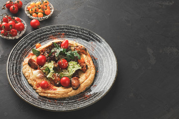 Hummus with vegetables and seafood on black background