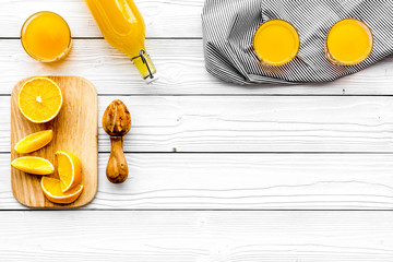 Make orange juice. Juicer, beverage in bottle and glasses near slices of oranges on white wooden background top view copyspace