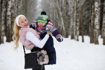 Fototapeta na wymiar Young mother walks on a winter day with a baby in her arms in th