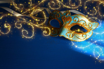 Image of elegant blue and gold venetian, mardi gras mask over blue background.