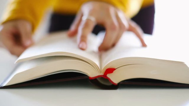 Close up of woman hands flipping book, reading book