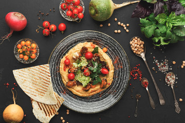 Hummus with vegetables and seafood on black background