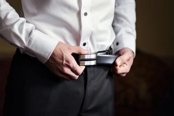 businessman putting on a belt, fashion and clothing concept,groom getting ready in the morning before ceremony