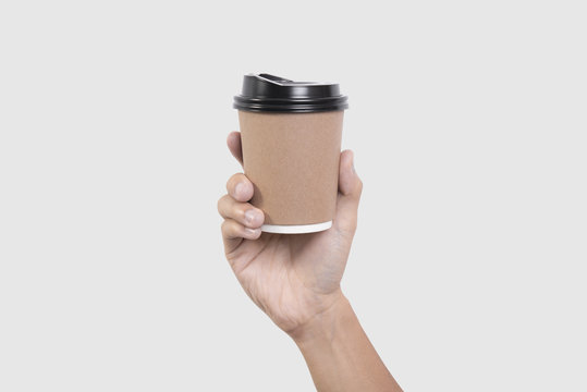hand holding coffee paper cup isolated on grey background. mock up for branding.