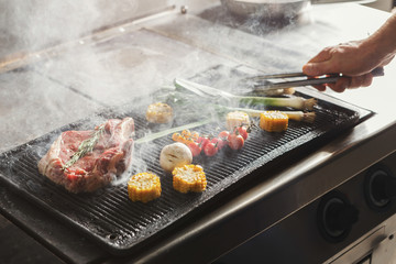 Chef cooking juicy beef steak at restaurant kitchen