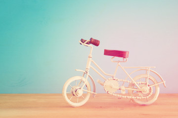Fototapeta na wymiar Vintage metal white bicycle toy over wooden table.