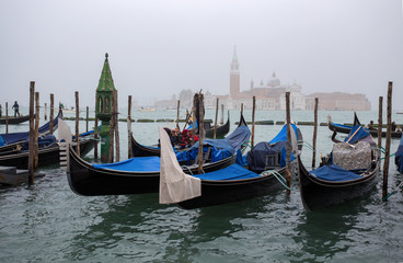 Fototapeta na wymiar VENICE (VENEZIA) ITALY, OCTOBER 18, 2017 - View of traditional Gondolas on Canal Grande in Venice in a foggy day with San Giorgio Island on the background, Italy