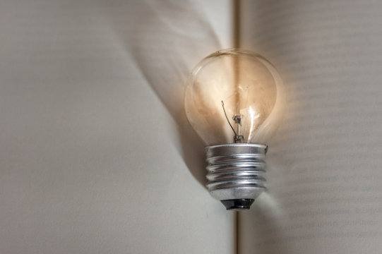 Yellow light bulb lamp over open books with blank pages