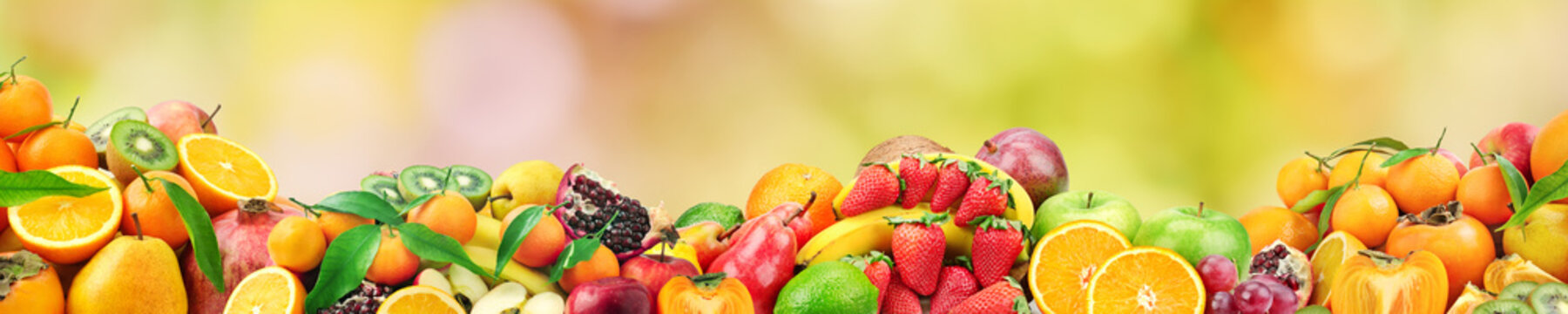 Fototapeta Fresh healthy fruits on natural blurred multicolored background.