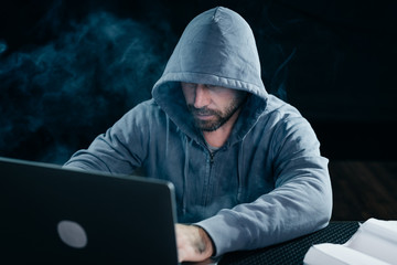 mysterious bearded man hacking does something illegal on a laptop, in the dark