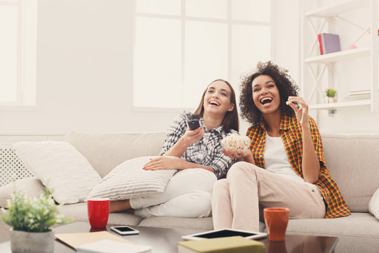 Smiling Female Friends Watching TV At Home