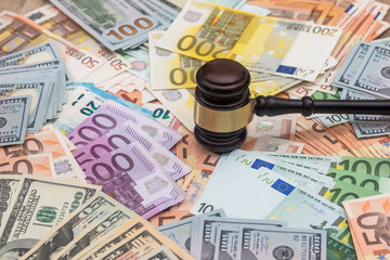 wooden hammer on dollar and euro banknotes