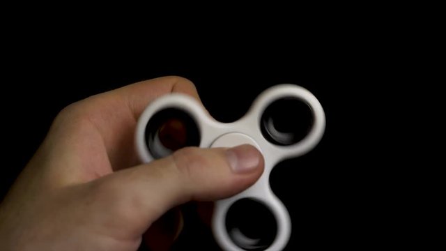 Fidget Spinner. White fidget spinner in a man hand. Male hand holding popular fidget spinner toy. Fidget spinner stress relieving toy white