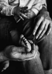 stylish black and white photo with the hands of parents and feet and the hands of their child