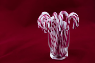 Glass with christmas candy canes. Isolated on a red background.