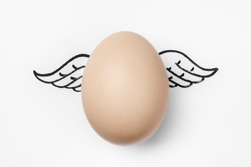 Chicken egg with painted wings on white background, close-up, top view