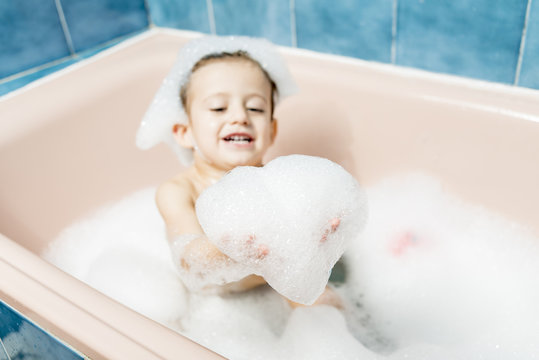 Child playing in the bath with the foam.
