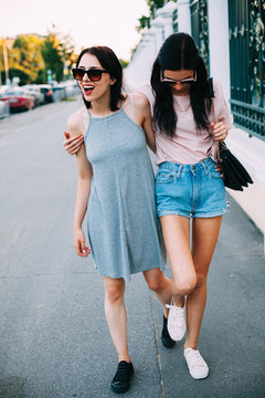 Two young women in sunglasses walking down the street