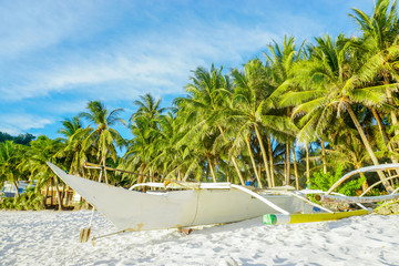 Boat on a tropical white sand beach with palm trees and blue sky, Phillippines Boracay