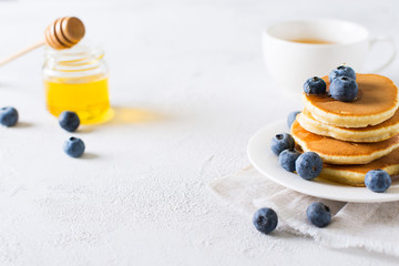 Pancakes breakfast, stack of homemade pancakes with blueberries and syrup over white background