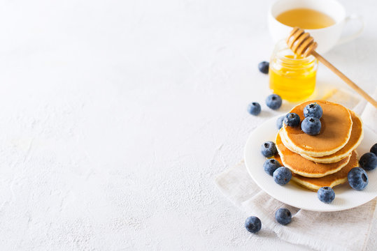 Pancakes breakfast, stack of homemade pancakes with blueberries and syrup over white background