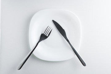 fork and knife on an empty white plate on a white background.
