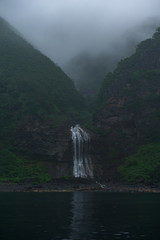 Waterfall dropping from high rocky cliffs into the ocean (Sea of Okhotsk) around the Shiretoko Peninsula, Hokkaido, Japan