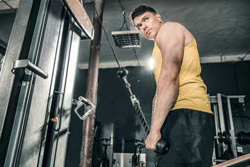 Fototapeta na wymiar Healthy man working out in gym doing triceps exercises. Photos taken on an atmospheric old gym