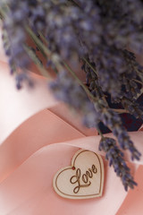 wooden heart on a background of a bouquet of lavender and a pink ribbon close-up
