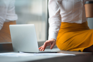 Naklejka premium Close up female hand typing in keypad of modern laptop in office. Occupation and technology concept