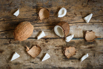 Fresh coconuts with spreaded chops and shell parts on wooden background