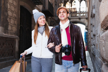 Portrait of adult tourists walking in hats and scarfs with bags