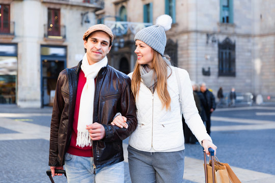 Man and woman walking at the historical streets with bags in autumn